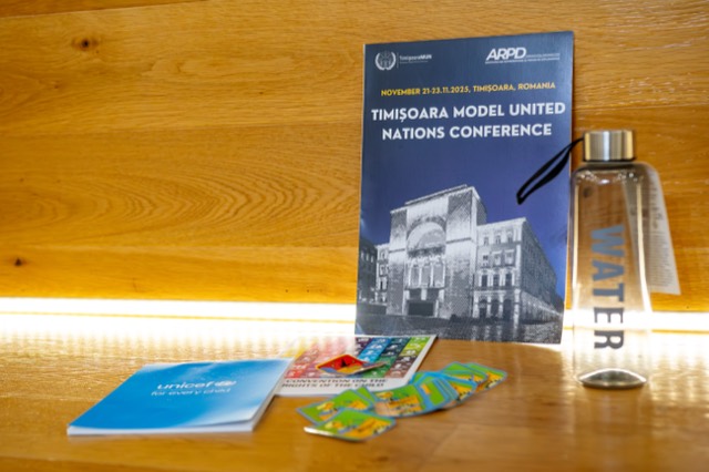 Timisoara International Model United Nations program booklet displayed with a water bottle and UNICEF materials.