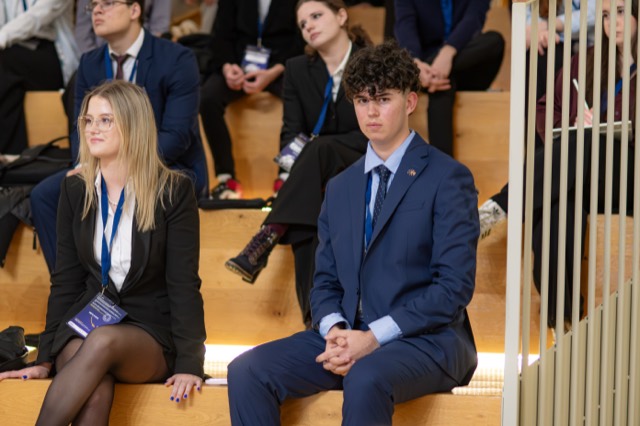 Two delegates seated in the front row follow the ceremony.