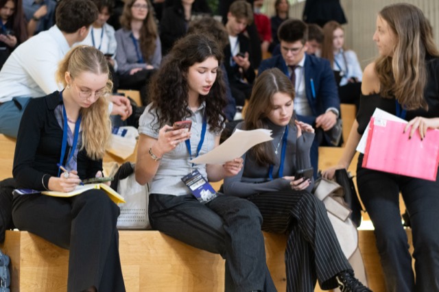 Delegates on the steps review papers and take notes before the session.