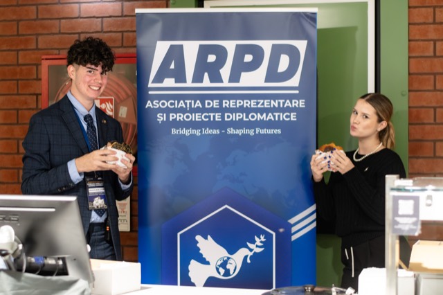 Two participants smile holding burgers beside the ARPD roll-up banner.