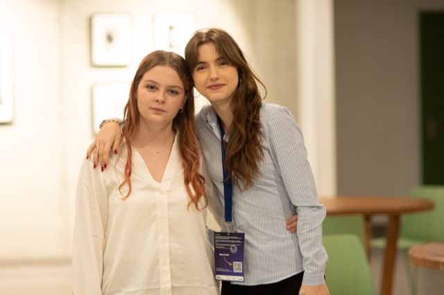Two delegates pose close together, one with an arm around the other's shoulder.