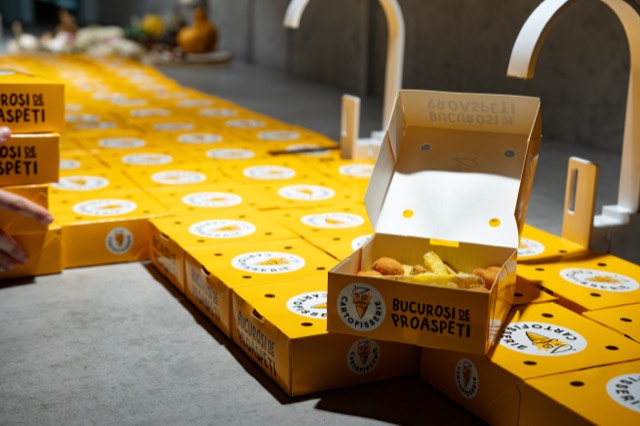 An opened box of fries sits atop rows of yellow boxes.